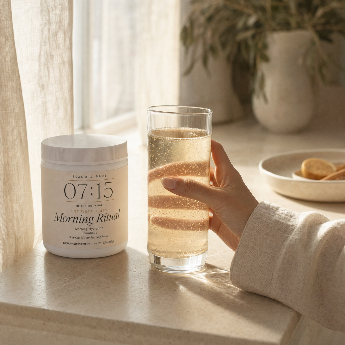 The first glass, held — morning light through linen
