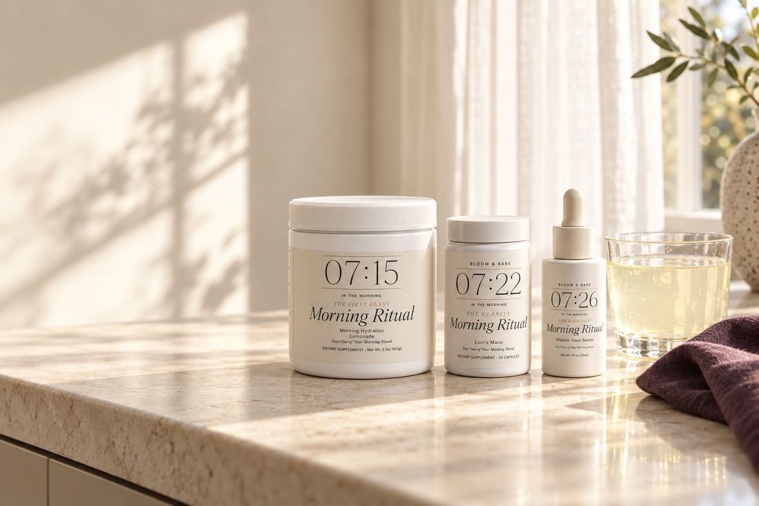 Bloom and Bare hydration powder, lion’s mane capsules and Vitamin Glow Serum beside a prepared glass on a morning counter